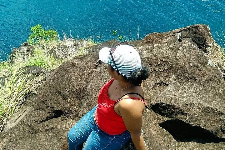 Woman sitting on rocky cliff overlooking the blue ocean at Pigeon Island.