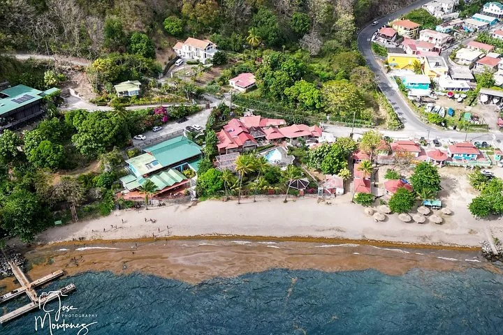 An aerial view of a coastal village with red-roofed houses and a beach.