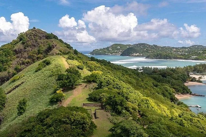 Lush green hills and ruins at Pigeon Island National Landmark overlooking the ocean.
