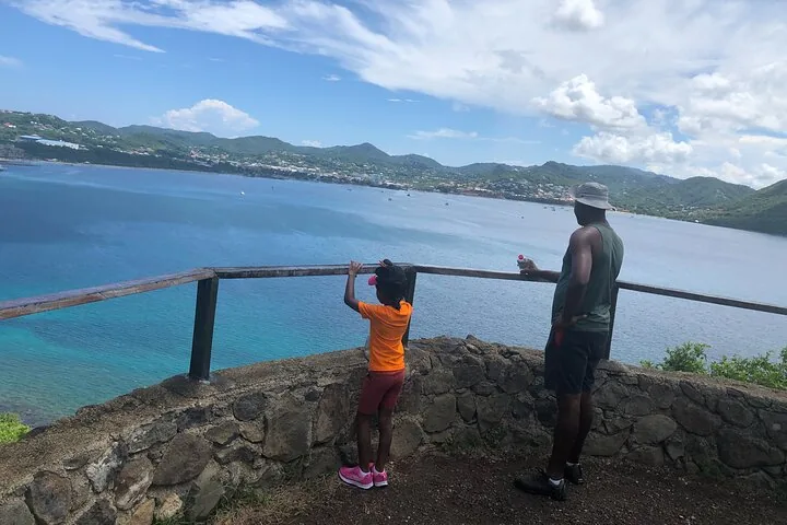 A man and a child looking out at the bay from a stone viewpoint.