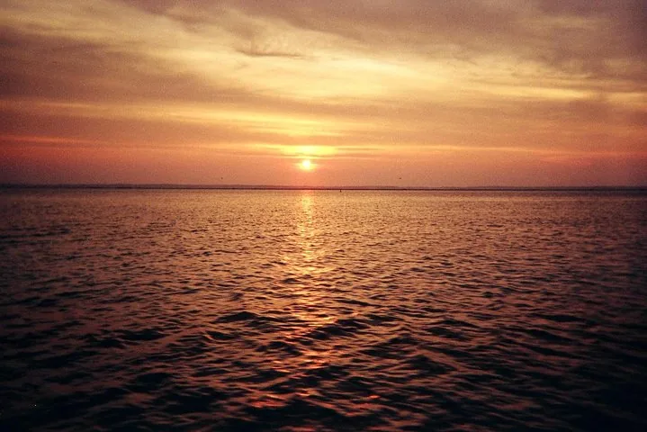 A serene sunset over a calm ocean with a bright horizon
